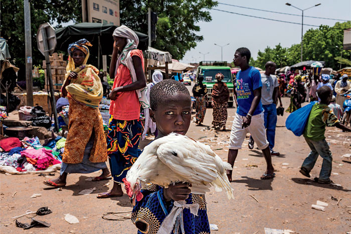  A Malian child holding a chicken in a Bamako market.   Photo: Marco Di Lauro/Reportage by Getty Images 